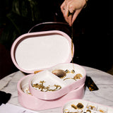 Rosa smyckeskrin från misou på marmor bord med en hand